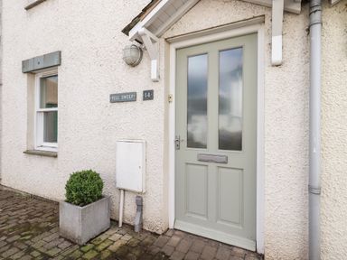 An exterior view of a front door with frosted glass panels a window and a potted plant at Fell Sweep in Keswick
