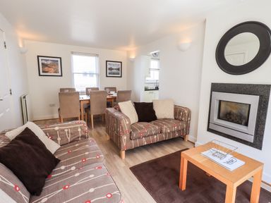A living room with two patterned sofas a wooden coffee table and a wall-mounted fireplace at Fell Sweep in Keswick