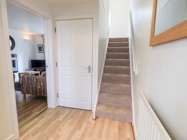 A hallway with stairs leading up and a doorway to a living room at Fell Sweep in Keswick