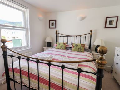 A bedroom with a metal bed frame with striped bedding and two bedside tables with lamps at Fell Sweep in Keswick