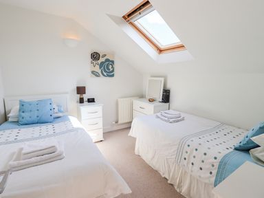 A bedroom with two single beds a bedside table a chest of drawers and a skylight window at Fell Sweep in Keswick