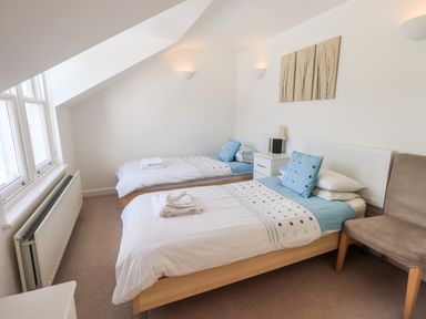 A bedroom with two single beds a bedside table a lamp a window and a chair at Fell Sweep in Keswick