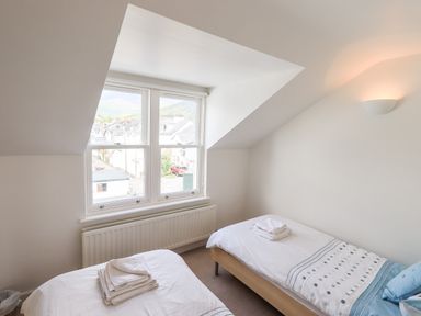A bedroom with two single beds and a window showing rooftops at Fell Sweep in Keswick