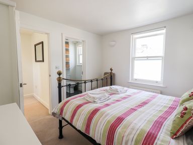 A bedroom with a striped bedspread and towels on the bed near a window at Fell Sweep in Keswick
