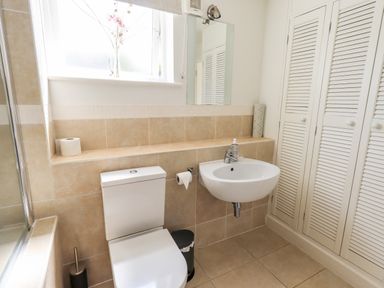 A bathroom with a toilet sink mirror and storage cupboards at Fell Sweep in Keswick
