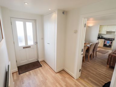 An entrance hall with a white front door a brown mat white walls and wooden flooring at Fell Sweep in Keswick