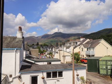 A street with white houses and parked cars with mountains in the background at Fell Sweep in Keswick