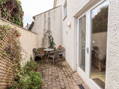 A narrow outdoor patio with a round table four chairs potted plants and glass double doors at Fell Sweep in Keswick