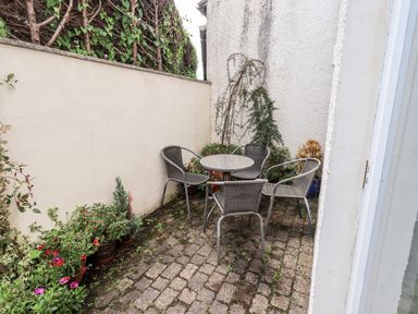 A small outdoor patio area with a round table and four chairs surrounded by plants at Fell Sweep in Keswick