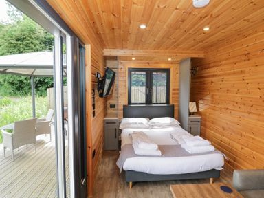 A bedroom with a bed and television at Maple Lodge at Bridge Lake Farm & Fishery Chacombe