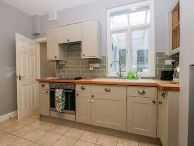 A kitchen with cabinets a sink and oven under a window at 7 Railway Cottages in Newby Bridge