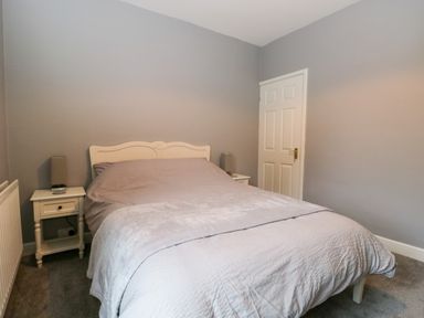 A bedroom with a double bed between two bedside tables with lamps at 7 Railway Cottages in Newby Bridge