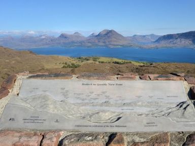 A viewing point with a stone map showing mountain names and a mountain range and a body of water in the background at Chapel House in Torridon