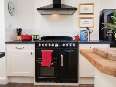 A kitchen with a black stove and oven with a red towel a red pot on the counter knives spice jars and a cookbook Ardlarach Lodge Cullipool Isle Of Luing