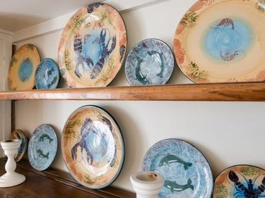 Decorative plates with sea life designs on wooden shelves including dolphins lobsters and shrimp at Ardlarach Lodge in Cullipool Isle Of Luing