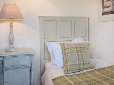 A bedroom with a bed with plaid pillows and blanket next to a bedside table with a lamp at Ardlarach Lodge in Cullipool Isle Of Luing