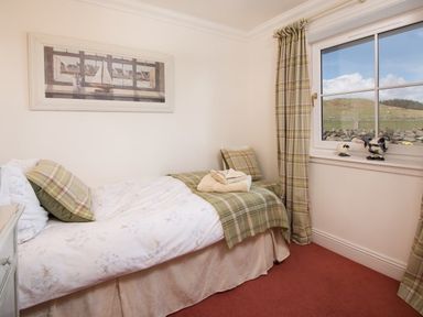 A bedroom with a single bed next to a window with curtains and a framed picture on the wall at Ardlarach Lodge in Cullipool Isle Of Luing