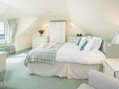 A bedroom with a bed and checkered blanket near a window with patterned curtains at Ardlarach Lodge in Cullipool Isle Of Luing