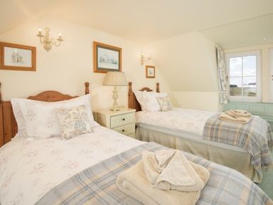 A bedroom with two single beds a lamp and framed pictures on the walls at Ardlarach Lodge Cullipool Isle Of Luing