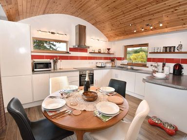 A kitchen with a round dining table set with plates and glasses at Skylarks in Ferintosh near to Dingwall