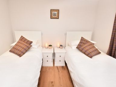 A bedroom with two single beds white bedding bedside tables and lamps at Skylarks in Ferintosh near to Dingwall