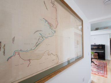 A framed map on a wall in a room with a piano and a table with flowers at Beltie Lodge in Borgue