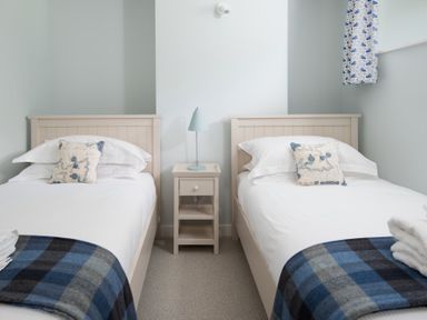 A bedroom with two single beds a nightstand and a lamp at Beltie Lodge in Borgue