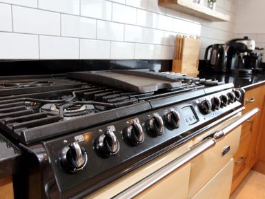 A kitchen stovetop with multiple burners and control knobs with a black countertop and white tiled backsplash at Eagle Lodge in Uig near Stornoway