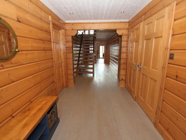 A wooden hallway with a bench and a round mirror stairs and multiple doors at Eagle Lodge in Uig near Stornoway