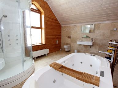 A bathroom with a shower cubicle a large bathtub a wall mounted sink and a toilet at Eagle Lodge in Uig near Stornoway
