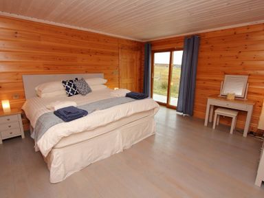 A bedroom with a double bed nightstand and dressing table with mirror at Eagle Lodge in Uig near Stornoway