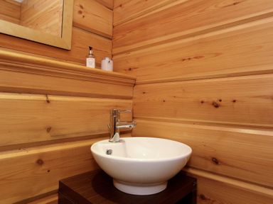 A bathroom corner with a white basin sink and chrome faucet on a wooden cabinet at Eagle Lodge in Uig near Stornoway