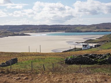 A coastal landscape with a sandy beach green fields stone walls and a white house at Eagle Lodge in Uig near Stornoway