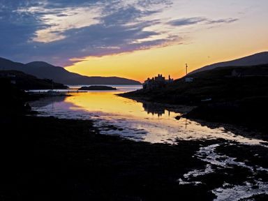 A sunset over a coastal inlet with houses and hills at Braemore Chalet Tarbert Isle Of Harris