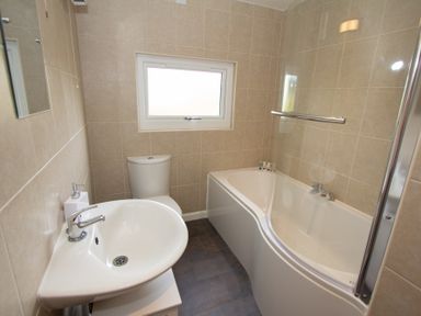A bathroom with a white sink toilet and bathtub with a window above the toilet at Braemore Chalet Tarbert Isle Of Harris