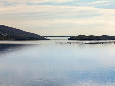 A body of water with a bridge in the distance and structures on the water at Braemore Chalet in Tarbert Isle Of Harris