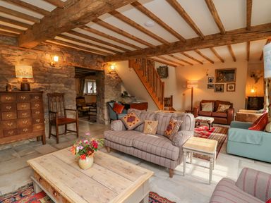 A living room with sofas a wooden coffee table flowers on the table and exposed wooden beams at Pen Bont Home Farm in Upper Chapel near Builth Wells