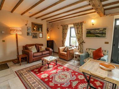A sitting room with sofas armchairs a patterned rug and wooden beams at Pen Bont Home Farm in Upper Chapel near Builth Wells