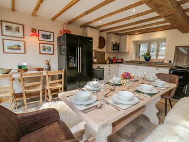 A kitchen and dining area with a set dining table and wooden chairs at Pen Bont Home Farm in Upper Chapel near Builth Wells
