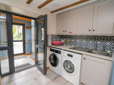 A utility room with washing machine dryer sink and cabinets at Pen Bont Home Farm Upper Chapel near Builth Wells