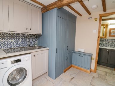 A kitchen with washing machine sink cabinets and blue storage units at Pen Bont Home Farm Upper Chapel near Builth Wells