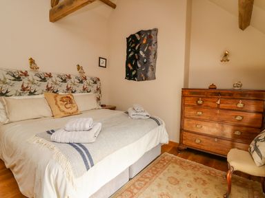 A bedroom with a bed folded towels and a wooden dresser at Pen Bont Home Farm in Upper Chapel near Builth Wells