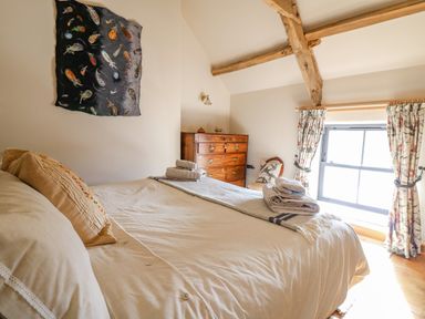 A bedroom with a bed towels on it a wooden chest of drawers a chair and a window with curtains at Pen Bont Home Farm in Upper Chapel near Builth Wells