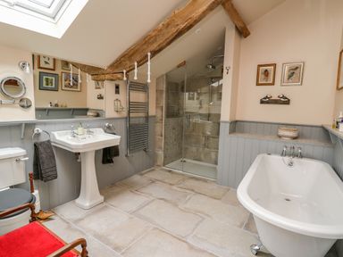 A bathroom with a bathtub, a sink, a toilet, a glass shower enclosure, a towel rack, and framed pictures on the walls at Pen Bont Home Farm in Upper Chapel near Builth Wells