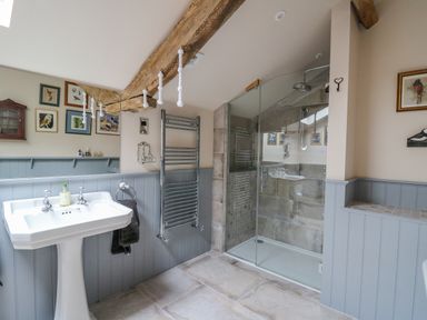 A bathroom with a pedestal sink a glass shower enclosure a towel rack and framed pictures on the wall at Pen Bont Home Farm in Upper Chapel near Builth Wells