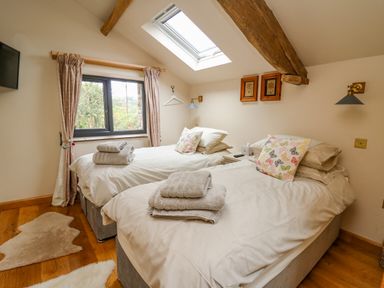 A bedroom with two single beds towels on beds a window with curtains and a skylight at Pen Bont Home Farm in Upper Chapel near Builth Wells