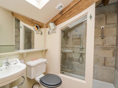 A bathroom with a sink, toilet, mirror, and shower at Pen Bont Home Farm in Upper Chapel near Builth Wells