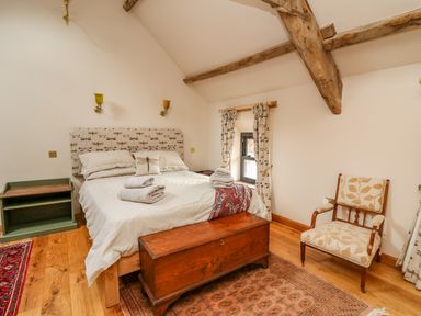 A bedroom with a bed towels wooden chest chair and exposed ceiling beams at Pen Bont Home Farm Upper Chapel near Builth Wells