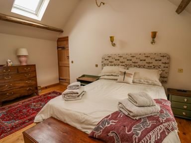 A bedroom with a bed with folded towels and a zebra blanket at Pen Bont Home Farm in Upper Chapel near Builth Wells