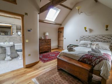 A bedroom with a double bed a wooden chest a dresser and an ensuite bathroom at Pen Bont Home Farm Upper Chapel near Builth Wells
